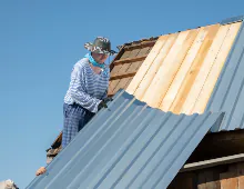 Akraba Construction the builder carefully lifts holds the roofing iron CPNKKVH