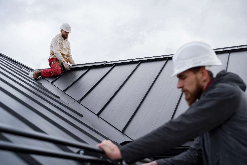 Two construction workers wearing hard hats carefully secure panels during a professional roof installation on a modern building.