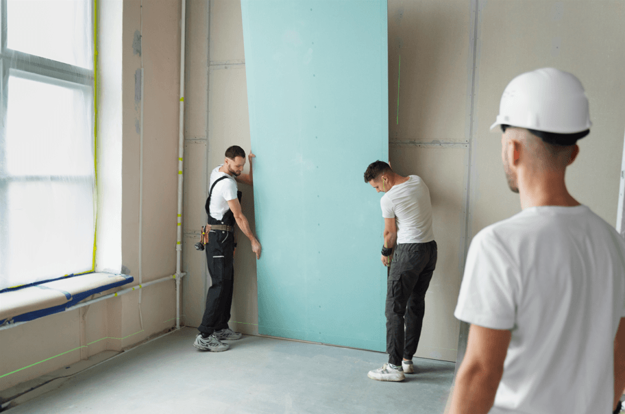 A professional construction team carefully installs and aligns large panels to ensure a smooth, high-quality result for expert drywall finishing.
