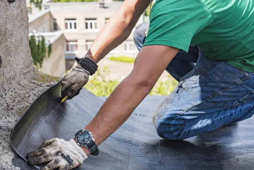 A technician carefully installs waterproofing material along a structural edge, ensuring a leak-proof finish during a professional roof repair.