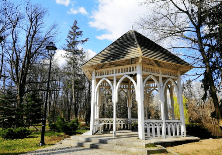 A wooden structure with overhead beams and white drapes provides a comfortable shaded area over lounge chairs, showcasing an elegant pergola design.