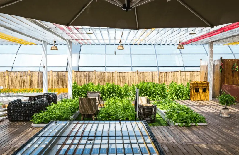 A sleek, dark-framed structure with a slatted roof provides a contemporary shaded retreat over a comfortable outdoor sofa, showcasing the latest in modern patio covers.