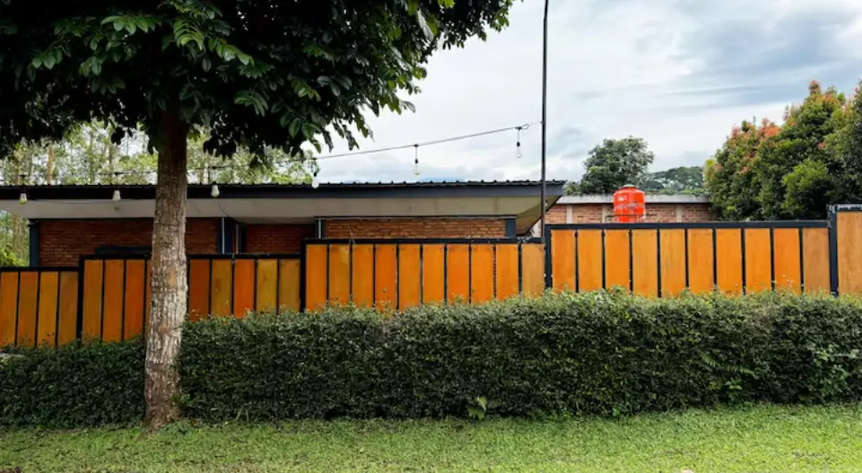 A fence style with vibrant wooden privacy wall with a black metal frame sits behind a manicured hedge, serving as a standout example of high-quality fence installation.