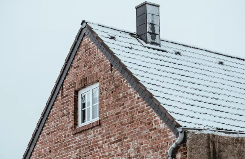 A professional technician works on a brick structure atop a residential roof to ensure a thorough chimney repair and long-lasting safety for the home.