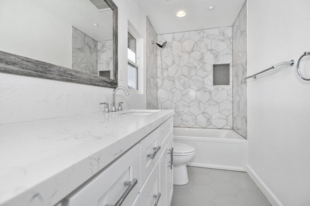 Bathroom remodel with white vanity, quartz top and hexagon marble tile tub surround by Akraba Remodeling in DFW