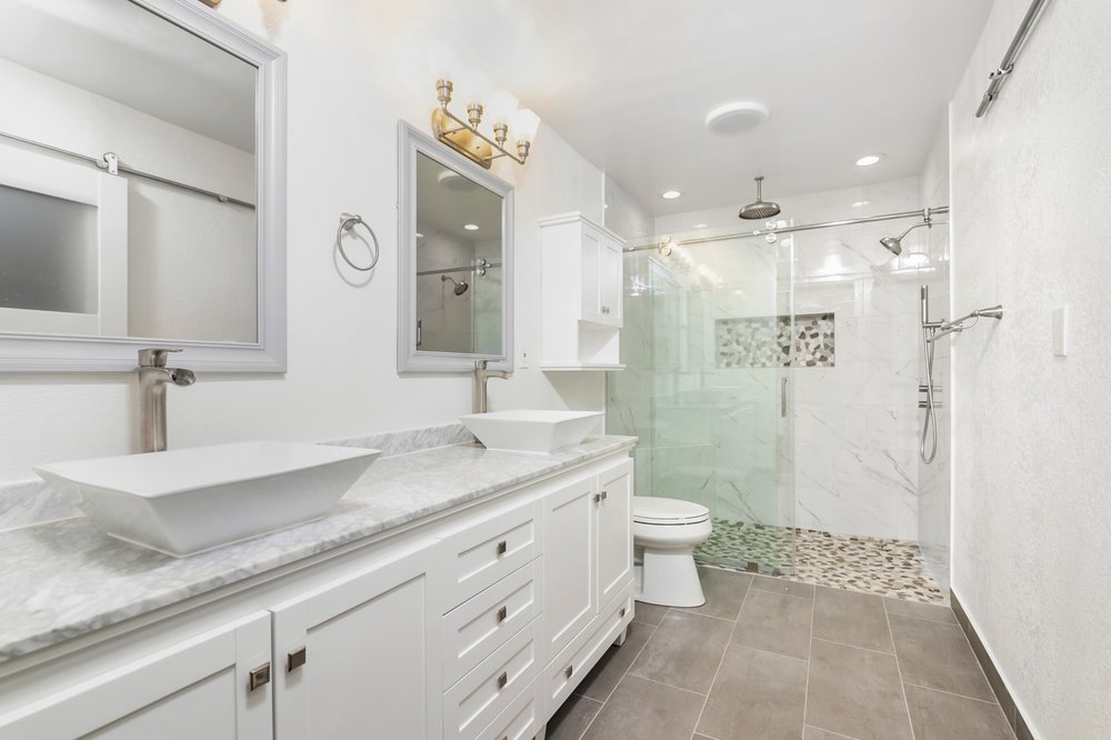 Double vanity bathroom remodel with vessel sinks and a pebble-floor walk-in shower by Akraba Remodeling