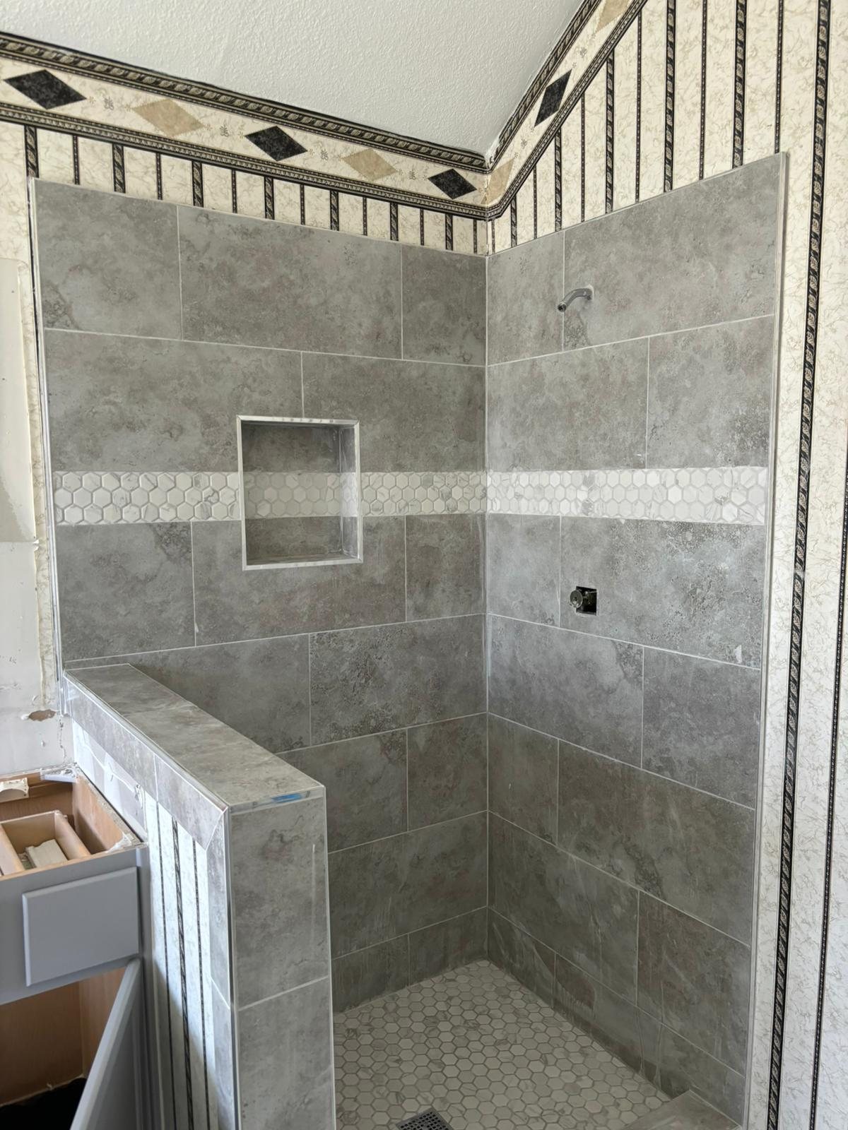 Gray tile walk-in shower with a built-in niche by Akraba Remodeling