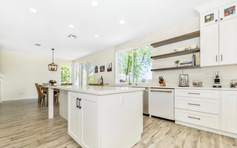 White shaker kitchen with a large island and open wood shelving, remodeled by Akraba Remodeling