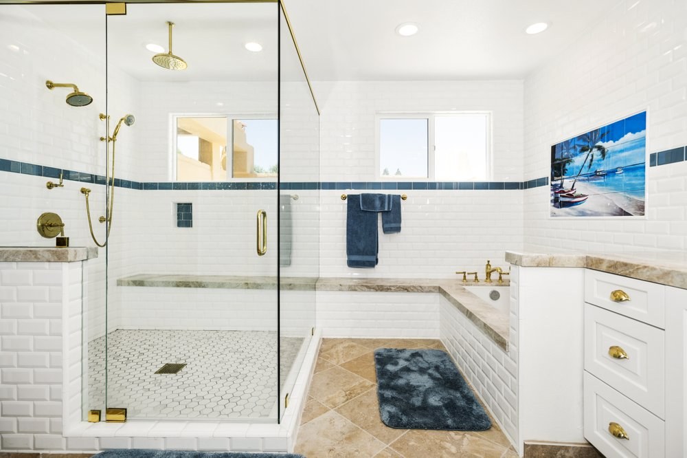 Walk-in glass shower with white subway tile, bench and gold fixtures in a DFW bathroom remodel