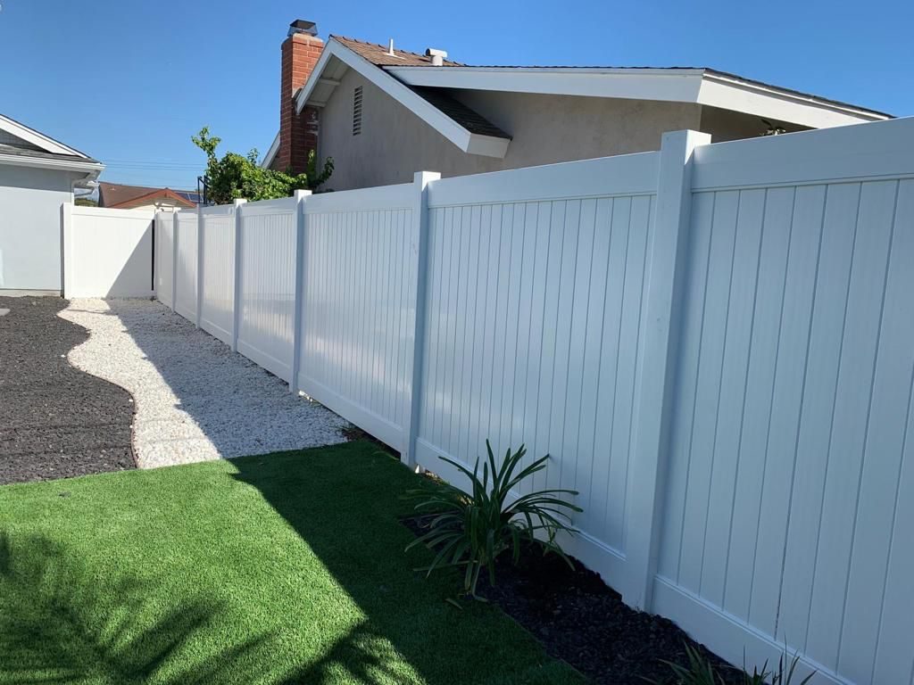 White vinyl fence beside a gravel path and artificial turf